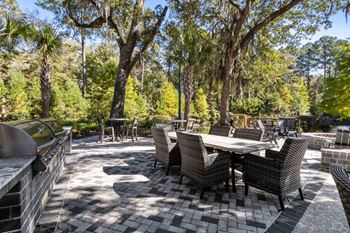 a patio with a table and chairs and trees